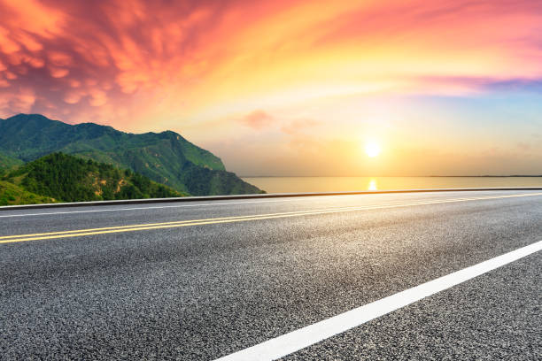 istock Asphalt road and green mountain with lake at sunset 1065263454
