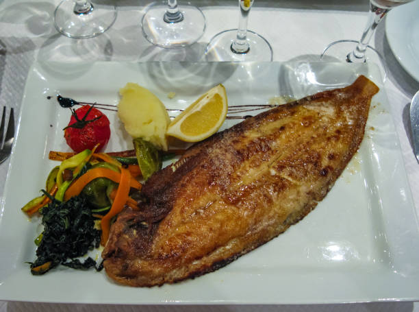 istock fried fish with wegitable and lemon on a dish 1065269532