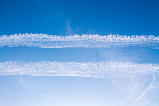 Two lanes in the blue sky from flying planes. Condensation trail