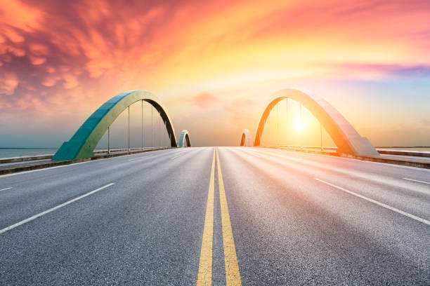 istock Asphalt road and dramatic sky with lake at sunset 1065278664