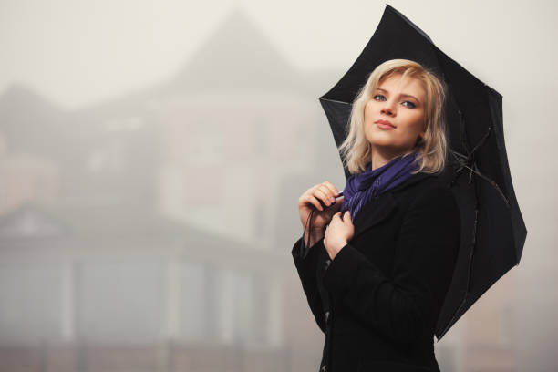 Young fashion woman with umbrella walking in a fog outdoor stock photo