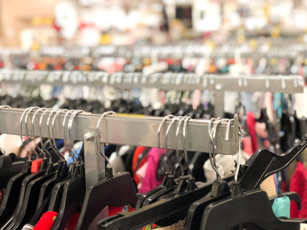 rows of multi-colored clothing on hangers in department store - textile textile industry warehouse store imagens e fotografias de stock