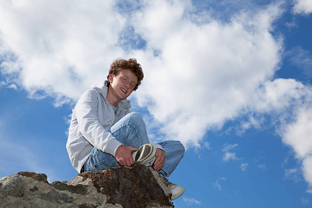 istock smiling teenager sitting on a wall 106529107