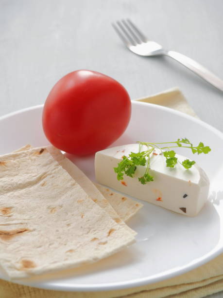 Healthy breakfast. Cheese with vegetables and cress salad served with fresh pita bread on white plate. Vertical. Selective focus on the center. stock photo