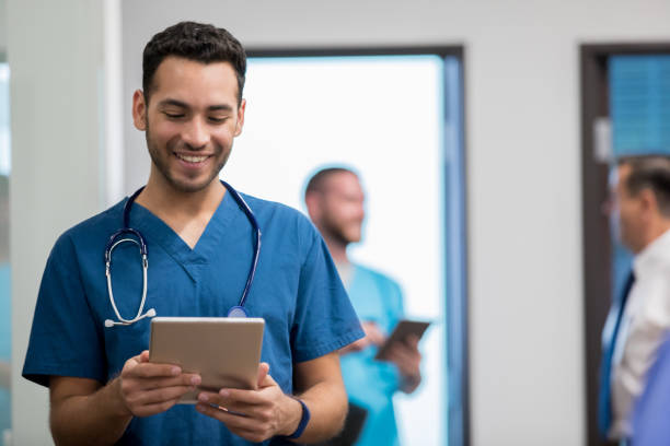 istock Young adult medical intern walking through hospital hallway while charting 1065295452