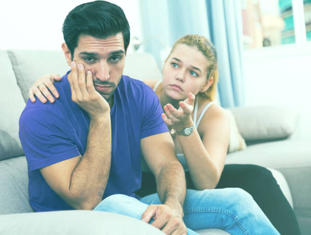 istock Ggirl comforting upset boyfriend on sofa 1065304126