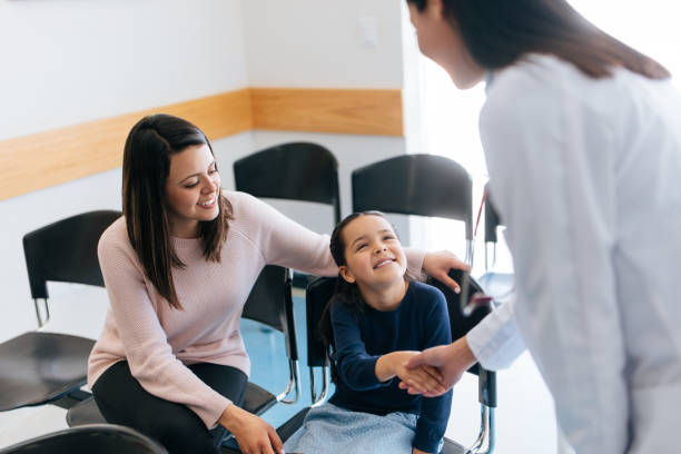Female doctor shaking hands with girl in waiting area A latin female doctor shaking the hand of a little girl sitting with her mother in the waiting area of a hospital, looking at each other and smiling. general military rank stock pictures, royalty-free photos & images