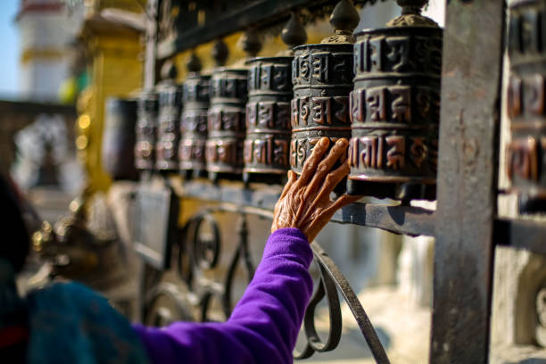 Old woman walking around the prayer wheels of Swayambhunath Stupa in Kathmandu, Nepal