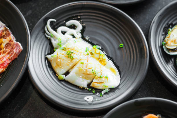 istock Fresh raw squid with sauce and sesame and scallion on black dish. 1065317456