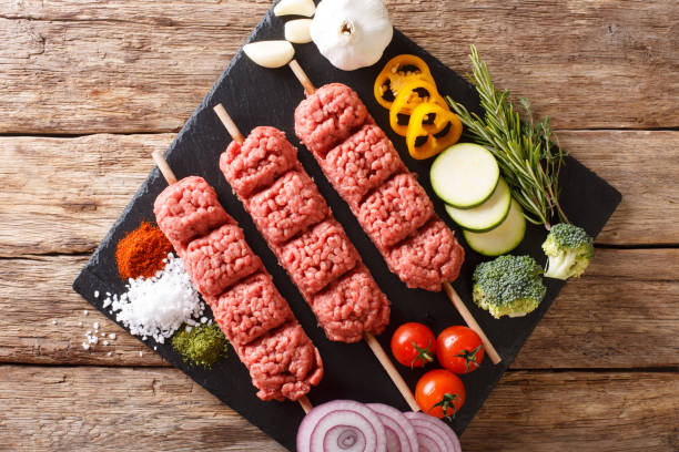 raw kebab of ground beef with ingredients and vegetables close-up.  Horizontal top view from above