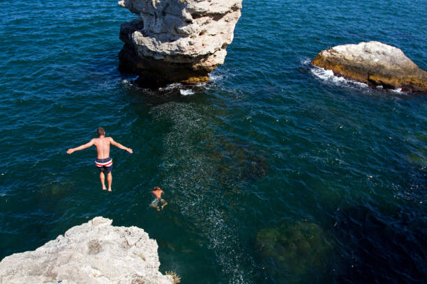 istock Young man making free cliff jump into the water 1065333528