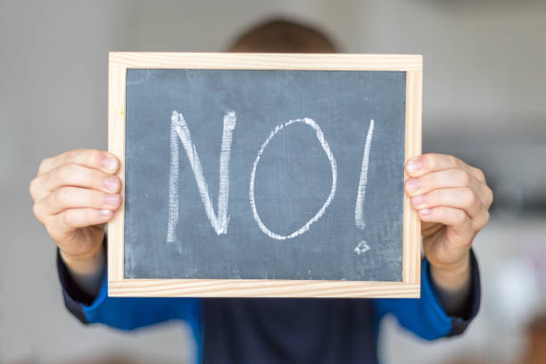 No boy holds blackboard with NO letters refusing photos stock pictures, royalty-free photos & images