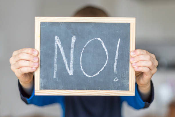 No boy holds blackboard with NO letters refusing stock pictures, royalty-free photos & images