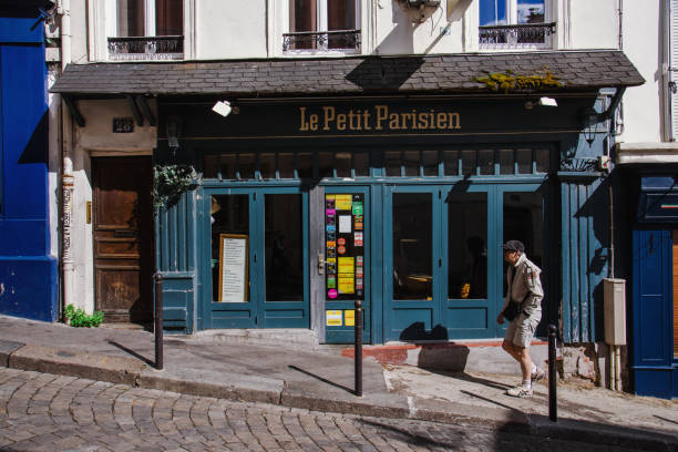 Paris, France - August 10, 2017. Typical Paris street with Le Petit Parisien french restaurant on Montmartre with walking single man in front.