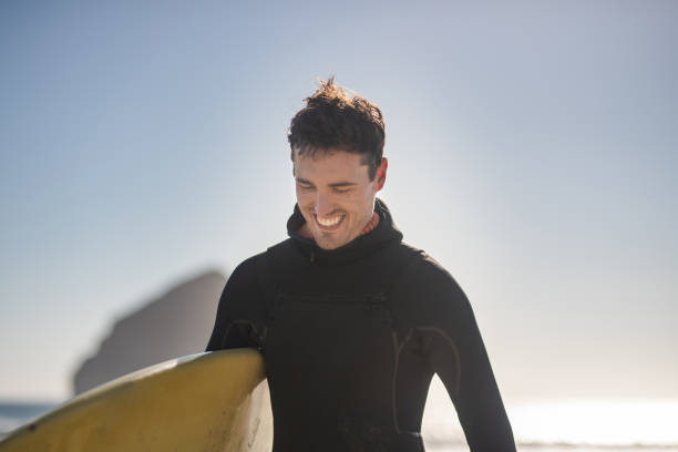 istock A male surfer walking along the beach 1065345092