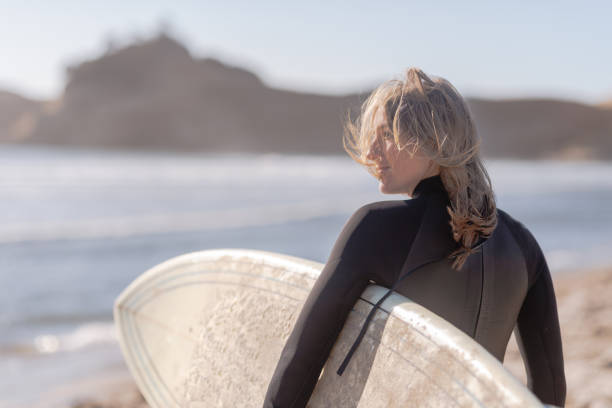 istock A female surfer walking along the beach 1065345130
