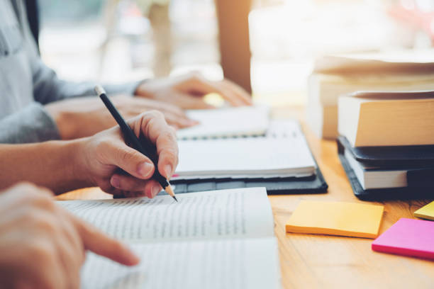 istock High school or college students studying and reading together in library 1065346054