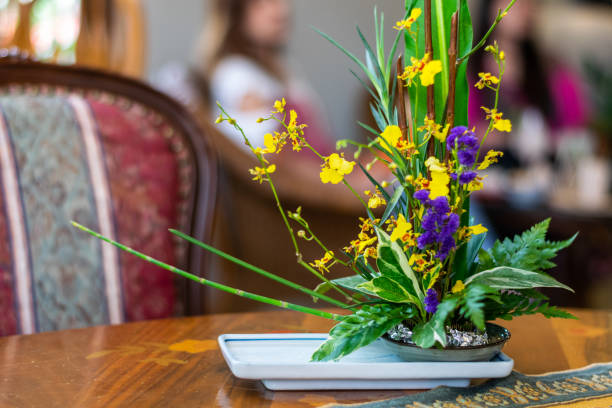 yellow orchids and violet tiny flowers in the ceramic vase on the wooden table. selective focus with blurred background. - fressness imagens e fotografias de stock