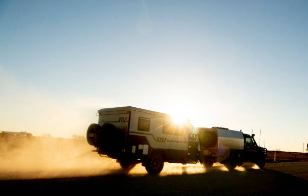 Outback Travelling Birdsville, Australia - June 21, 2018: A 4wd towing a caravan is seen travelling along a dirt road on the South Australia/Queensland border in the late afternoon. ian stock pictures, royalty-free photos & images
