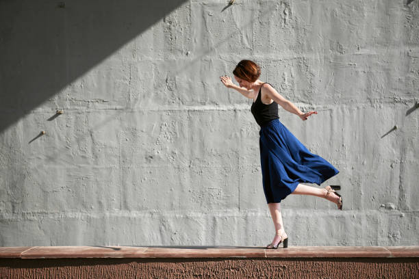 istock young girl posing against a concrete wall, dressed in black, hard light and shadows 1065352410