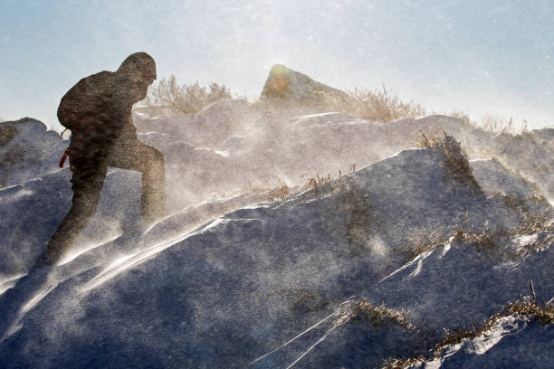 Young woman climbing a mountain in an extreme weather conditions of a severe blizzard