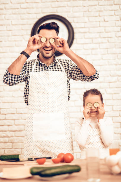 istock Dad and Daughter with Sliced Cucumbers near Eyes. 1065363030