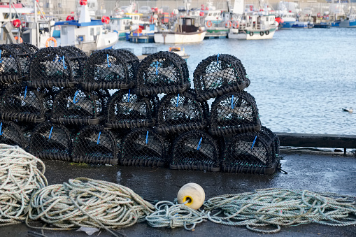 Stacked lobster fishing pots netted boxes at harbour wall uk