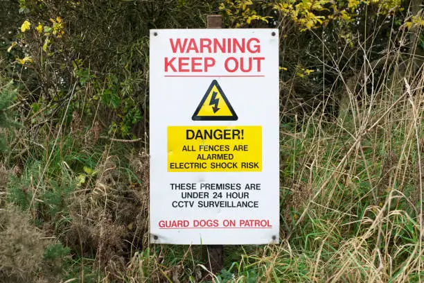 Electric fence and guard dog dangerous building construction site keep out health and safety signs uk