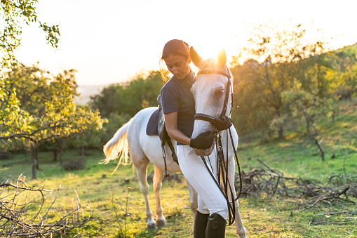 Woman hugging her horse at sunset in orchid