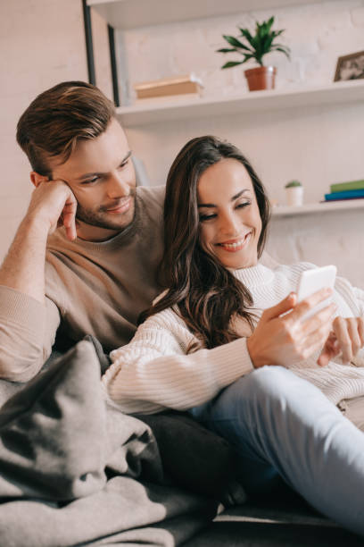 istock smiling young couple using smartphone together on couch at home 1065392022