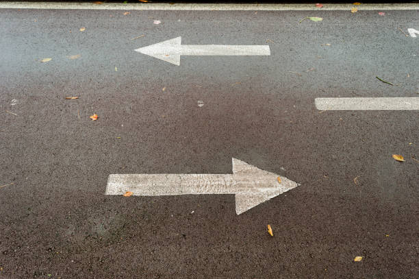 asphalt road with drawn arrows pointing to two directions. Making decisions and making choices stock photo