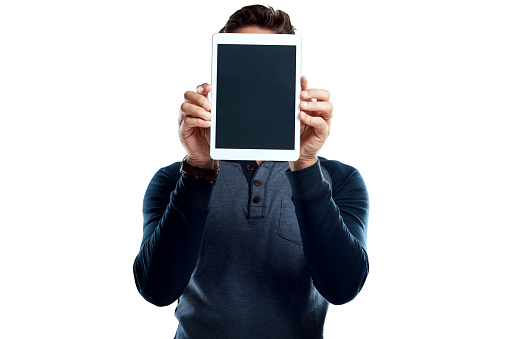 Studio shot of a young man holding a digital tablet with a blank screen against a white background