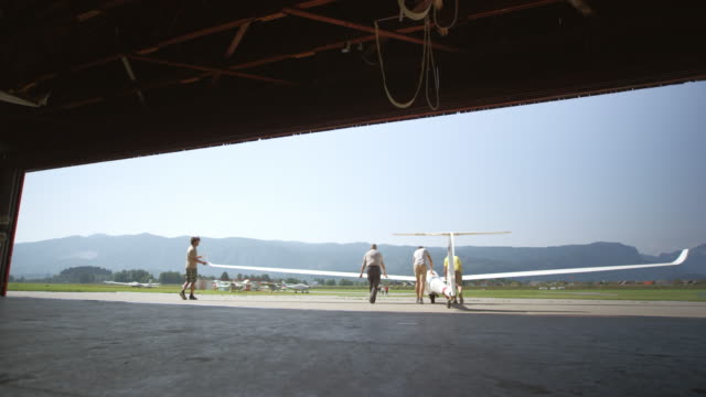Men taking a glider out of the hangar