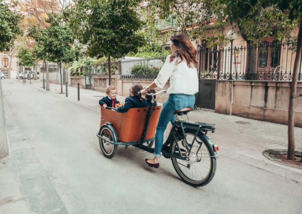 Mother riding bicycle Mother riding bicycle with children on it cargo bike photos stock pictures, royalty-free photos & images