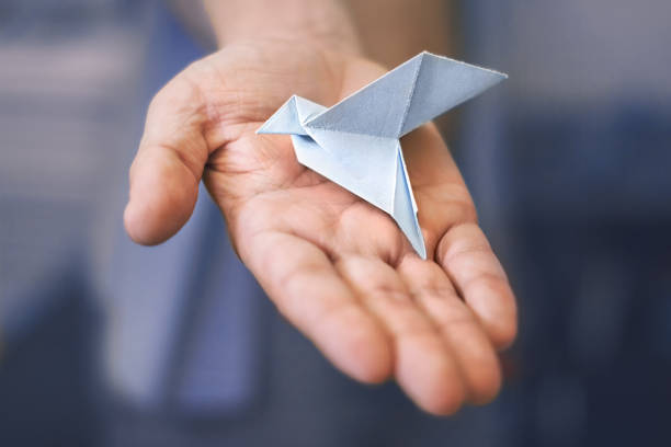 istock male right palm with a paper blue dove on blue background 1065395218