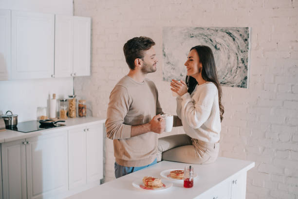 istock smiling young couple having breakfast together and chatting at home 1065395580