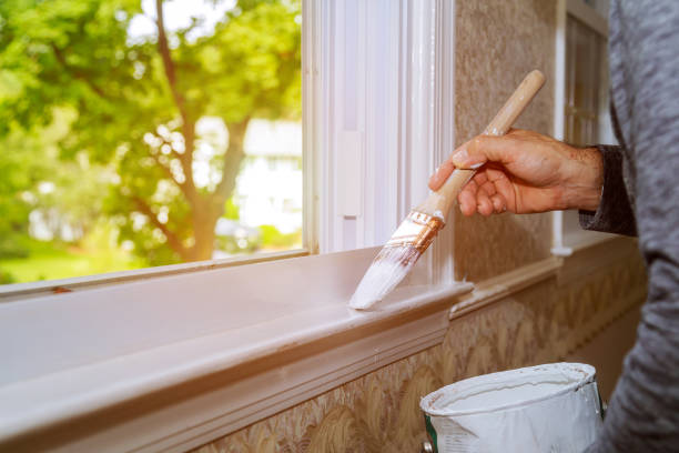 Male hands repairs painting window trim at home closeup