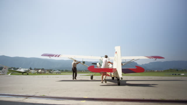 Men taking a light aircraft out of the hangar