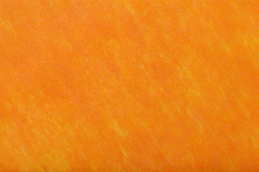 Construction of a bright orange background with light yellow spots of felt fabric, closeup. Texture of woolen matt textile. Cloth backdrop.