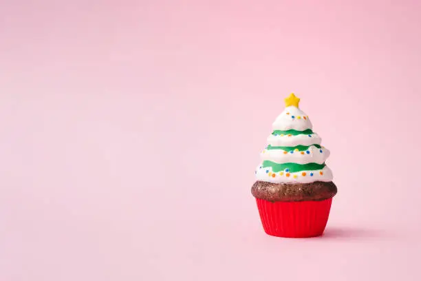 Photo of Christmas tree cupcake on pink background with copy space.