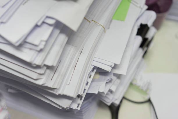 Many paper stacks lay messy on white table in the storage room.