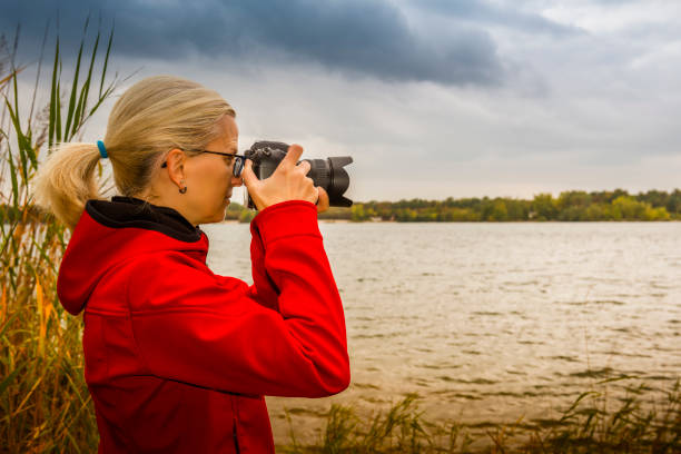 istock Woman with digital camera taking pictures on a lake 1065433342