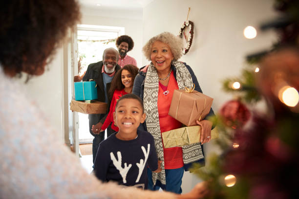 Grandparents Being Greeted By Family As They Arrive For Visit On Christmas Day With Gifts Grandparents Being Greeted By Family As They Arrive For Visit On Christmas Day With Gifts multi generation family christmas stock pictures, royalty-free photos & images