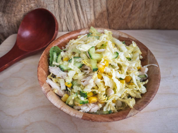 istock Diet salad from Beijing cabbage, boiled chicken, canned corn, fresh cucumbers, greens in a bamboo dish. Big maiden spoon. 1065437214