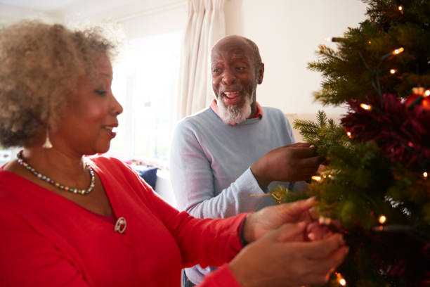 istock Senior Couple Hanging Decorations On Christmas Tree At Home Together 1065439584