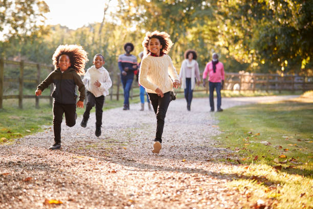 enfants en cours d’exécution avant comme multi génération famille profiter ensemble de promenade d’automne dans la campagne - smiling little girls little boys autumn photos et images de collection