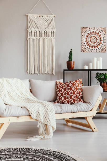 istock Patterned pillow and blanket on sofa in grey boho living room interior with poster. Real photo 1065439852