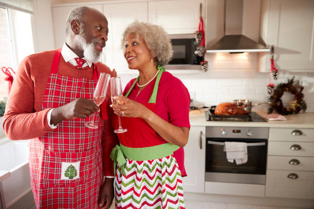 istock Senior black couple wearing aprons take a break from preparing Christmas dinner to make a toast, close up 1065443336