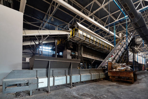 istock Conveyor belt at recycling plant transports garbage inside drum filter or rotating cylindrical sieve with trommel or screen for sorting pieces of garbage into fractions of various sizes 1065443546