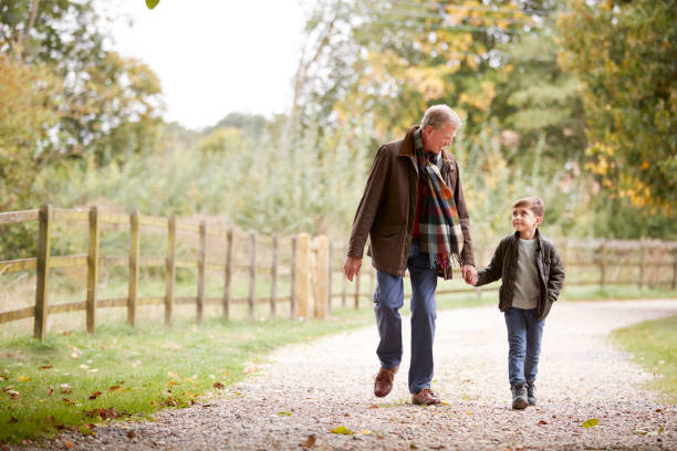 дедушка с внуком на осенней прогулке в сельской местности вместе - grandparent grandfather walking grandchild стоковые фото и изображения